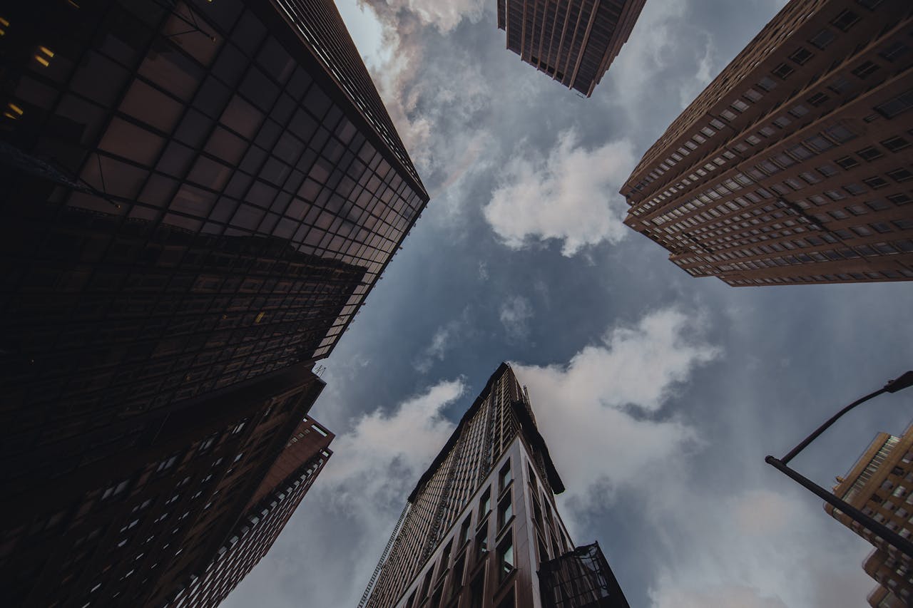 services-03 A low-angle view of towering city skyscrapers against a dramatic cloudy sky.